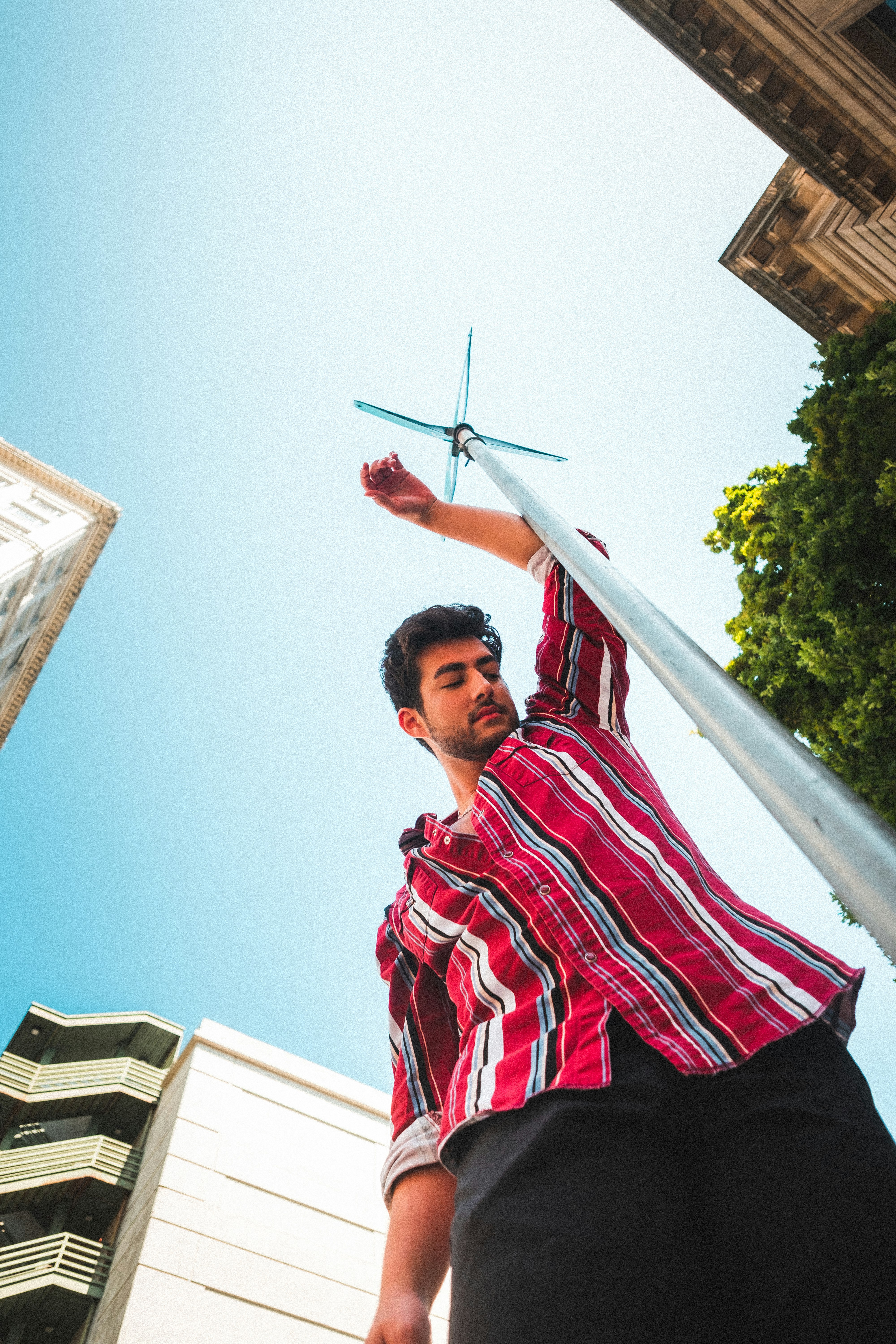 man in red and white stripe polo shirt standing on roof during daytime